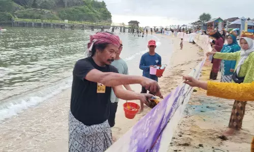 Aksi seniman Nasirun di Pantai Drini, Gunung Kidul, melukis di kanvas sepanjang 100 meter